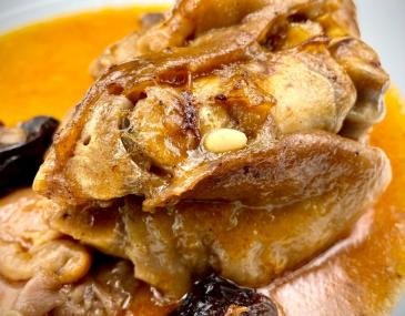 Peus de porc ofegats amb prunes i pinyons